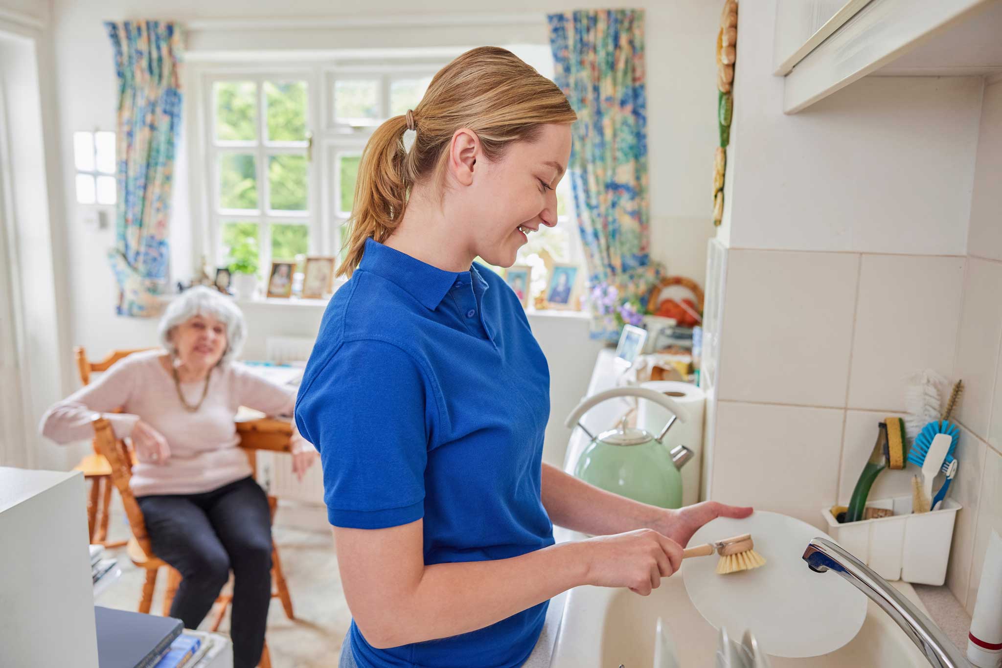 female caregiver washing patient's dishes